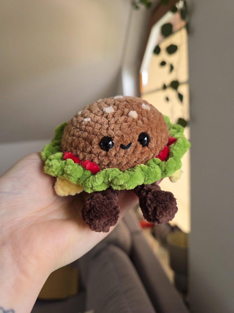 Two handmade mini burger crochet amigurumi being held side by side
